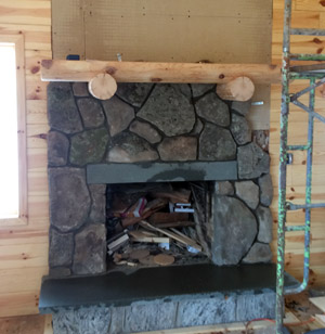 Progress photo of the fireplace fieldstone veneer, pine log mantle, bluestone hearth and header.